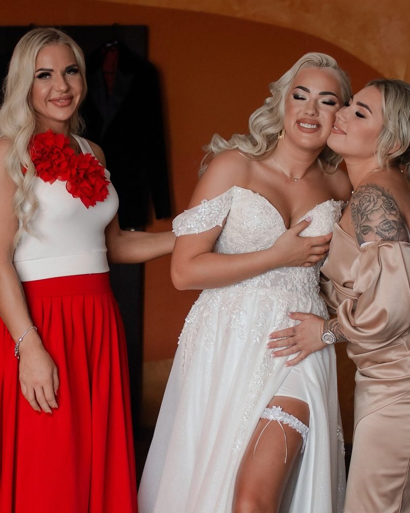 Nuotaka apsikabinusi su dviem moterimis, matoma keliaraiščio detalė – vestuvių fotosesija Šiauliuose