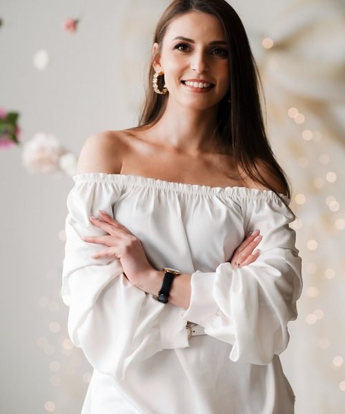 Moters portretas studijoje, sukryžiuotos rankos, fone gėlės ir girliandos – asmeninė fotosesija Šiauliuose
