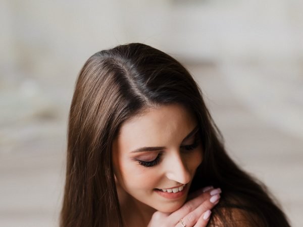 Moteris šypsosi žvelgdama žemyn, ranka prie smakro – asmeninė fotosesija Šiauliuose