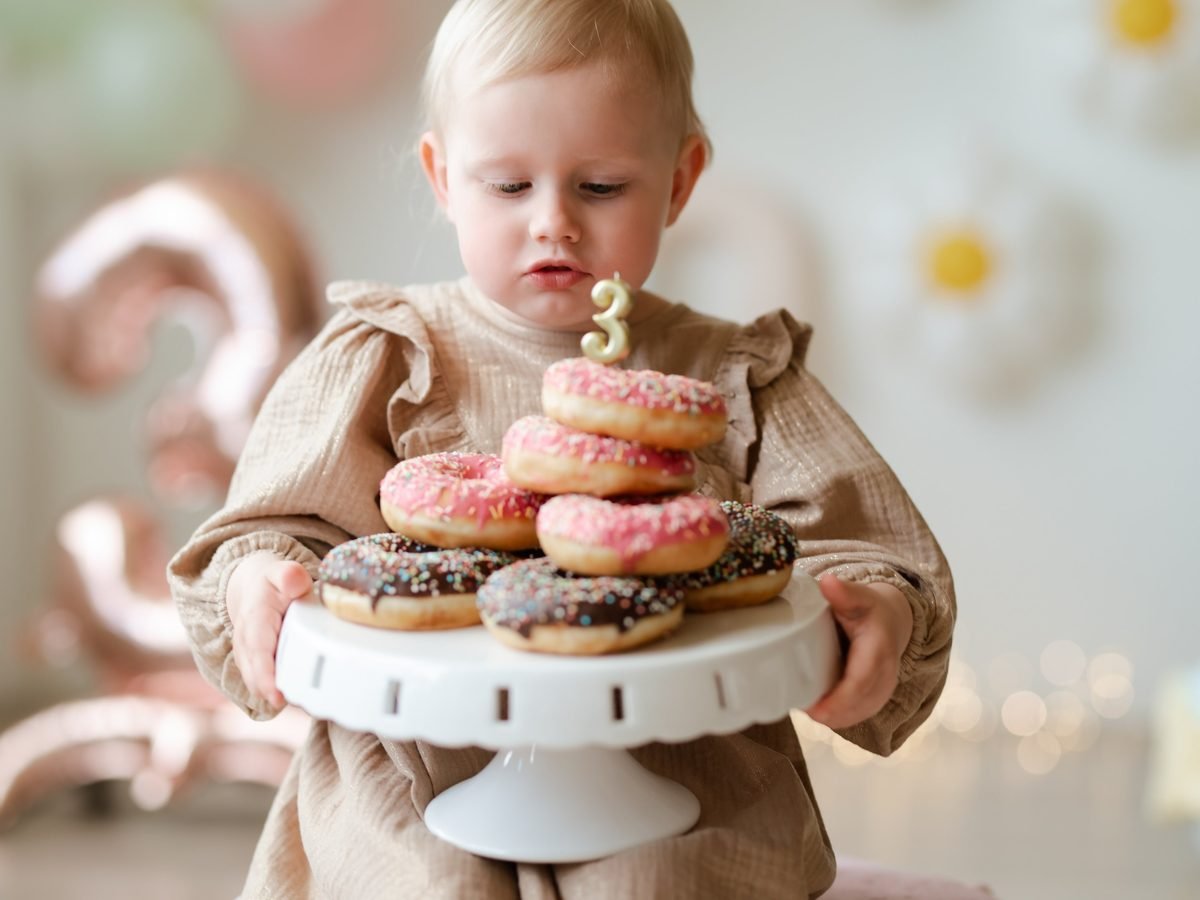 Mažametė laiko spurgų stovą su gimtadienio žvakute – cake smash fotosesija Šiauliuose
