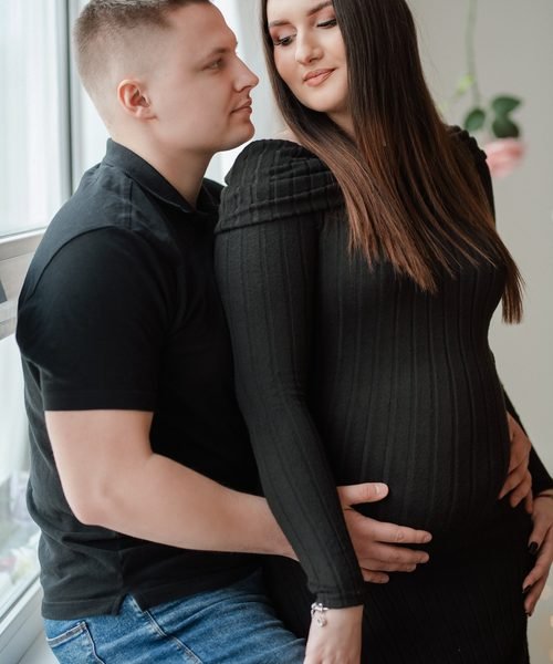 Vyro ir nėščios moters glaudus apsikabinimas artimu planu – laukimo fotosesija Šiauliuose